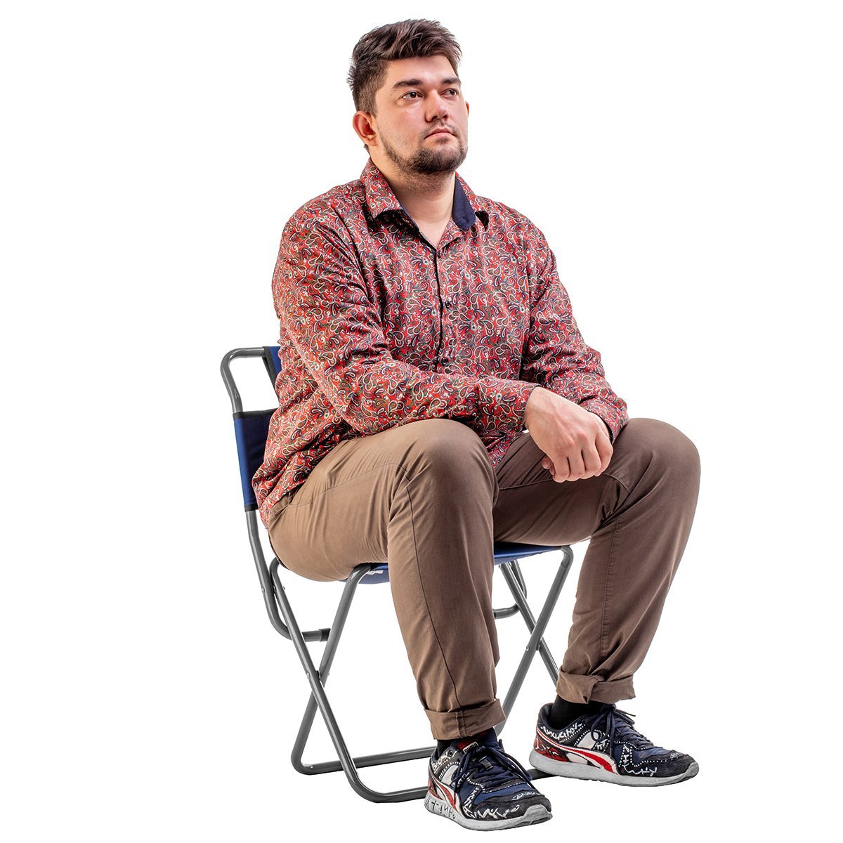 Man wearing a beard, shirt, trousers and snickers sitting on the folding camping chair