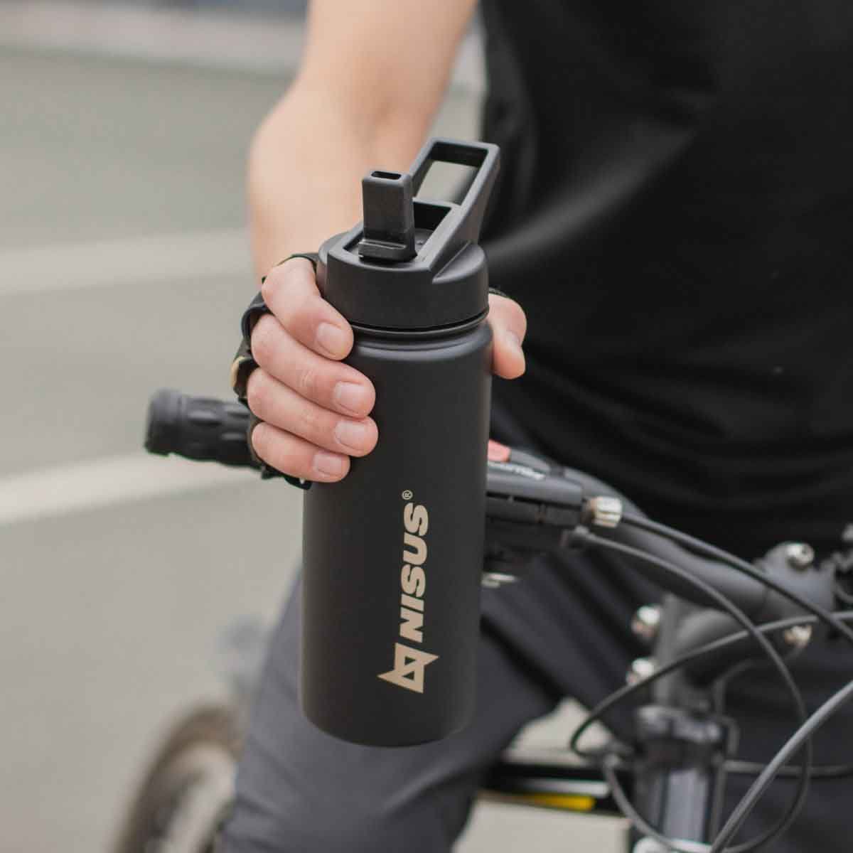 A man on the bike holding the Stainless Steel Insulated Sport Water Bottle with 3 Lid Types, 18 oz, black