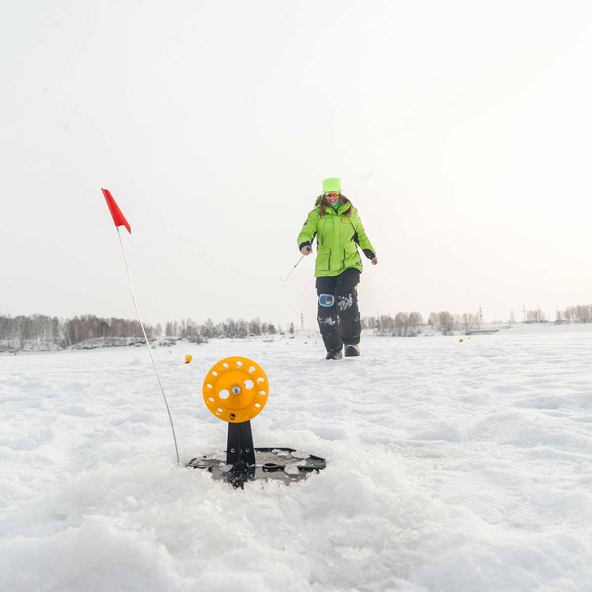 A woman fishing with an Equipped Tip-up Pop-Up Integrated Hole-Cover