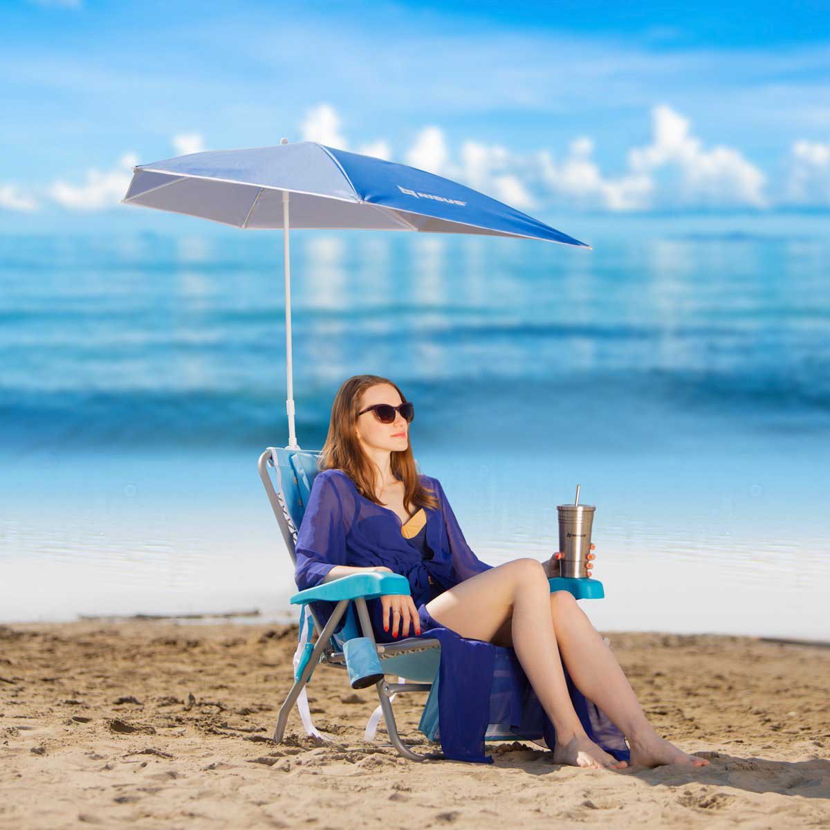 A girl sitting on the beach in a Premium Backpack Beach Chair with Cooler Bag and Clip On Umbrella